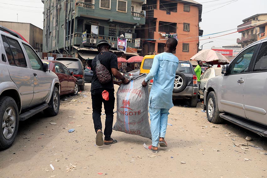 Adeyemi Emmanuel (L) carries a sack filled with pieces of frames he collected from a frame shop at Aroloya market in Lagos, Nigeria