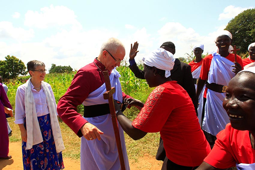 A woman wraps Archbishop of Canterbury Justin Welby in a piece of cloth upon his arrival at Mirieyi settlement camp in Adjumani district during his visit to South Sudanese refugees in Uganda on August 2, 2017.