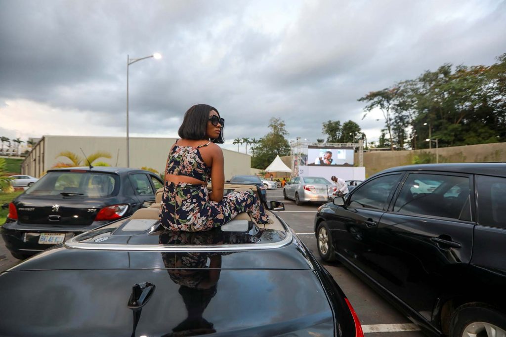 A woman sits on a car to watch "Living in bondage" movie at a drive-in cinema, following the relaxation of lockdown, amid the coronavirus disease (COVID-19) outbreak in Abuja, Nigeria on May 20, 2020.