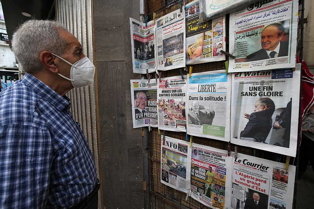 A man reads headlines reporting the death of former Algerian President Abdelaziz Bouteflika, at a newsstand in Algiers on September 19.