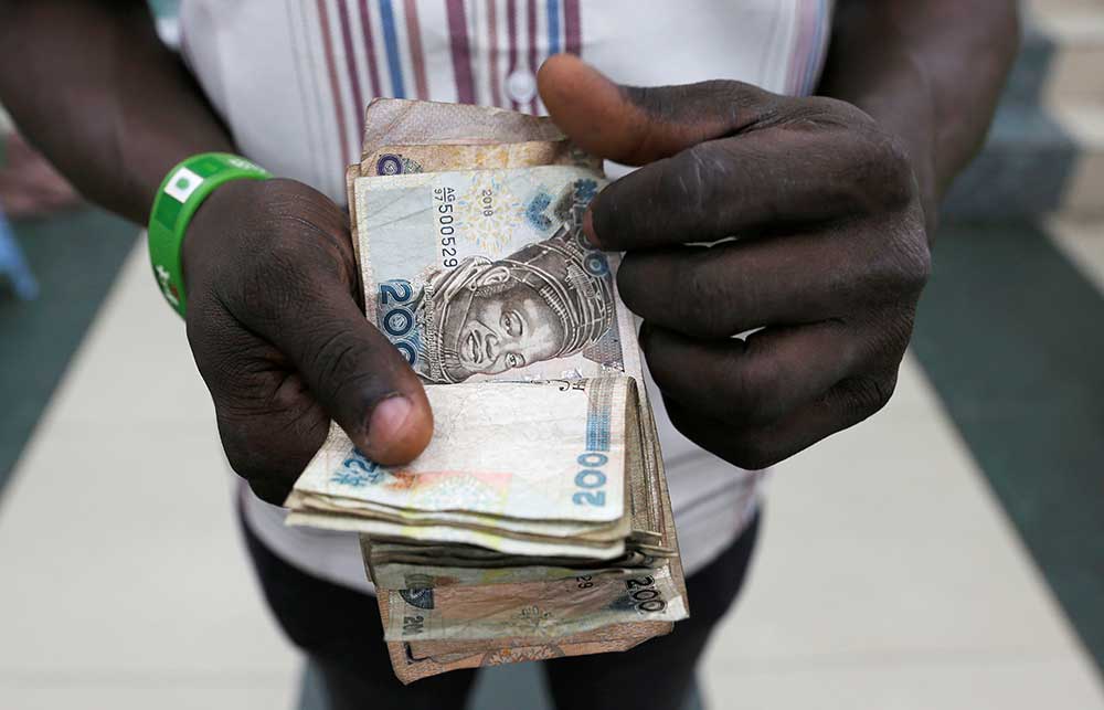 A vendor counts Nigerian naira banknotes inside a shop in Idumota Market, in Lagos, Nigeria.