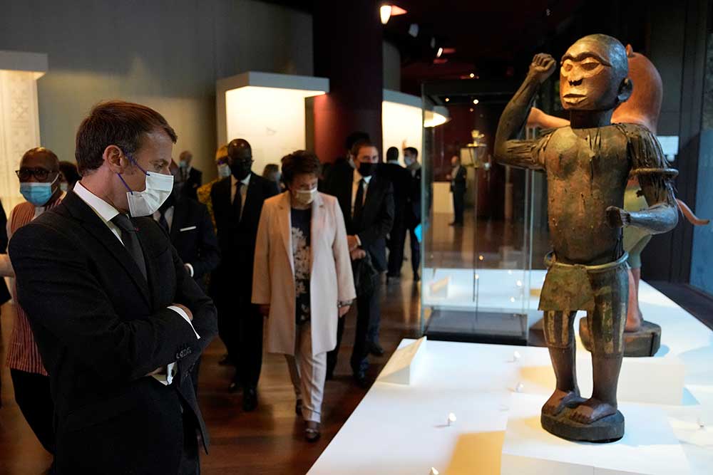 French President Emmanuel Macron looks at a 19th-century statue of King Ghezo, ruler of the Kingdom of Dahomey from 1818-1858, at the Quai Branly museum in Paris in October 2021. The statue is part of the exhibition “Restitution of 26 works from the royal treasury in Abonney,” featuring 26 artworks from the Kingdom of Dahomey that had been seized by French colonial soldiers in 1892. They were returned to Benin on November 10, a landmark in African countries’ long fight to recover looted artifacts.