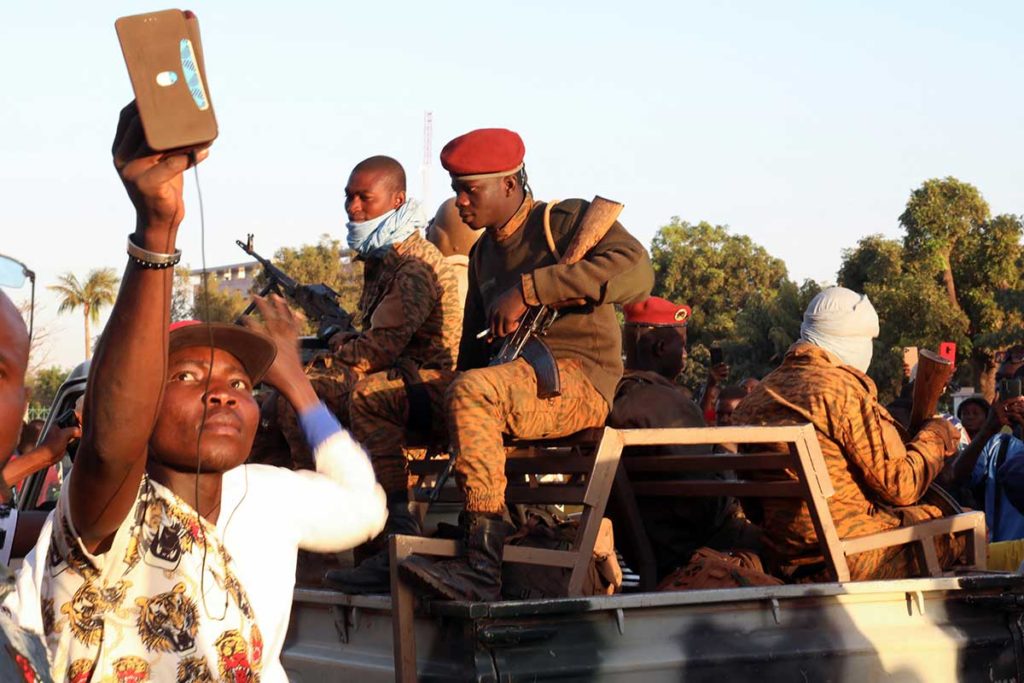 A man uses his mobile phone beside army soldiers during fighting in Ouagadougou January 24.