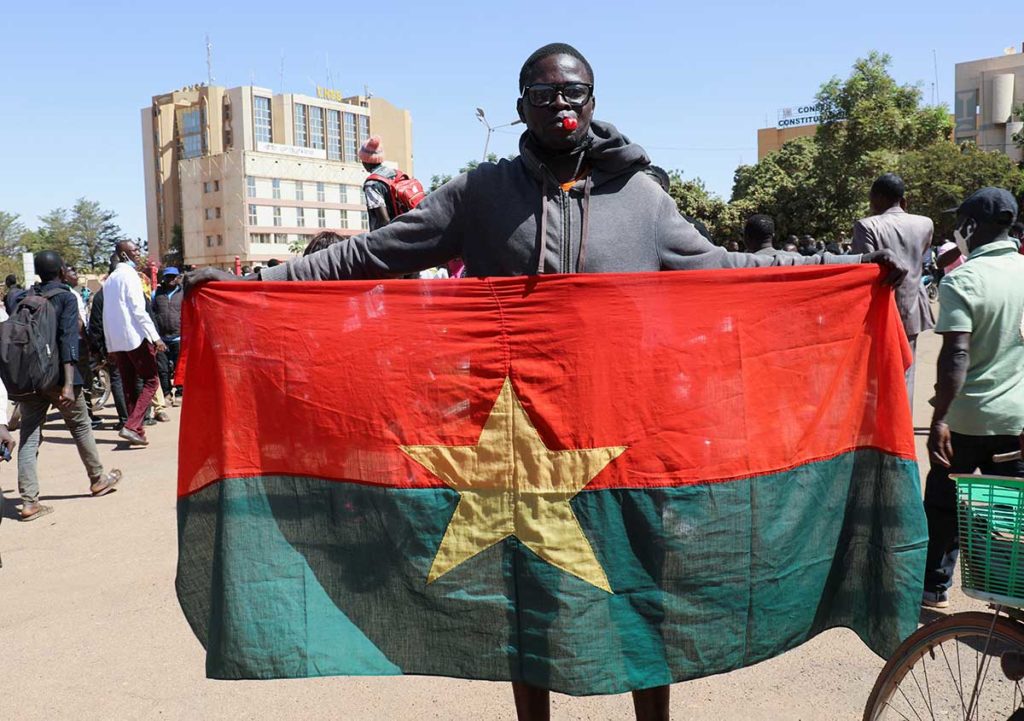 A man in Ouagadougou holds a Burkinabe flag on January 24 to show support for the military attempt to oust President Kabore.