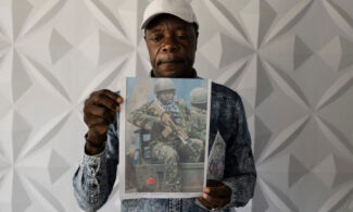 Charles Ojiambo Mutoka, 72, stands with pictures of his son Oscar during a press conference in Nairobi in January. Oscar was killed in August 2025 while fighting alongside Russian soldiers against Ukraine.