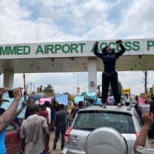 A demonstrator stands atop a vehicle and shouts slogans as others carry banners while blocking a road leading to the airport, during a protest over alleged police brutality, in Lagos, Nigeria on October 12, 2020. A demonstrator stands atop a vehicle and shouts slogans as others carry banners while blocking a road leading to the airport, during a protest over alleged police brutality, in Lagos, Nigeria on October 12, 2020.