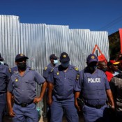 Police officers keep watch as members of South Africa's Economic Freedom Fighters party (EFF) hold placards during a protest on Africa Day outside the French Embassy, in Pretoria, South Africa, on May 25, 2022. Police officers keep watch as members of South Africa's Economic Freedom Fighters party (EFF) hold placards during a protest on Africa Day outside the French Embassy, in Pretoria, South Africa, on May 25, 2022.